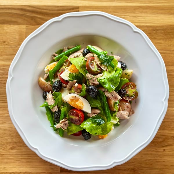A vibrant Niçoise salad with tuna, green beans, olives, tomatoes, and hard-boiled eggs.