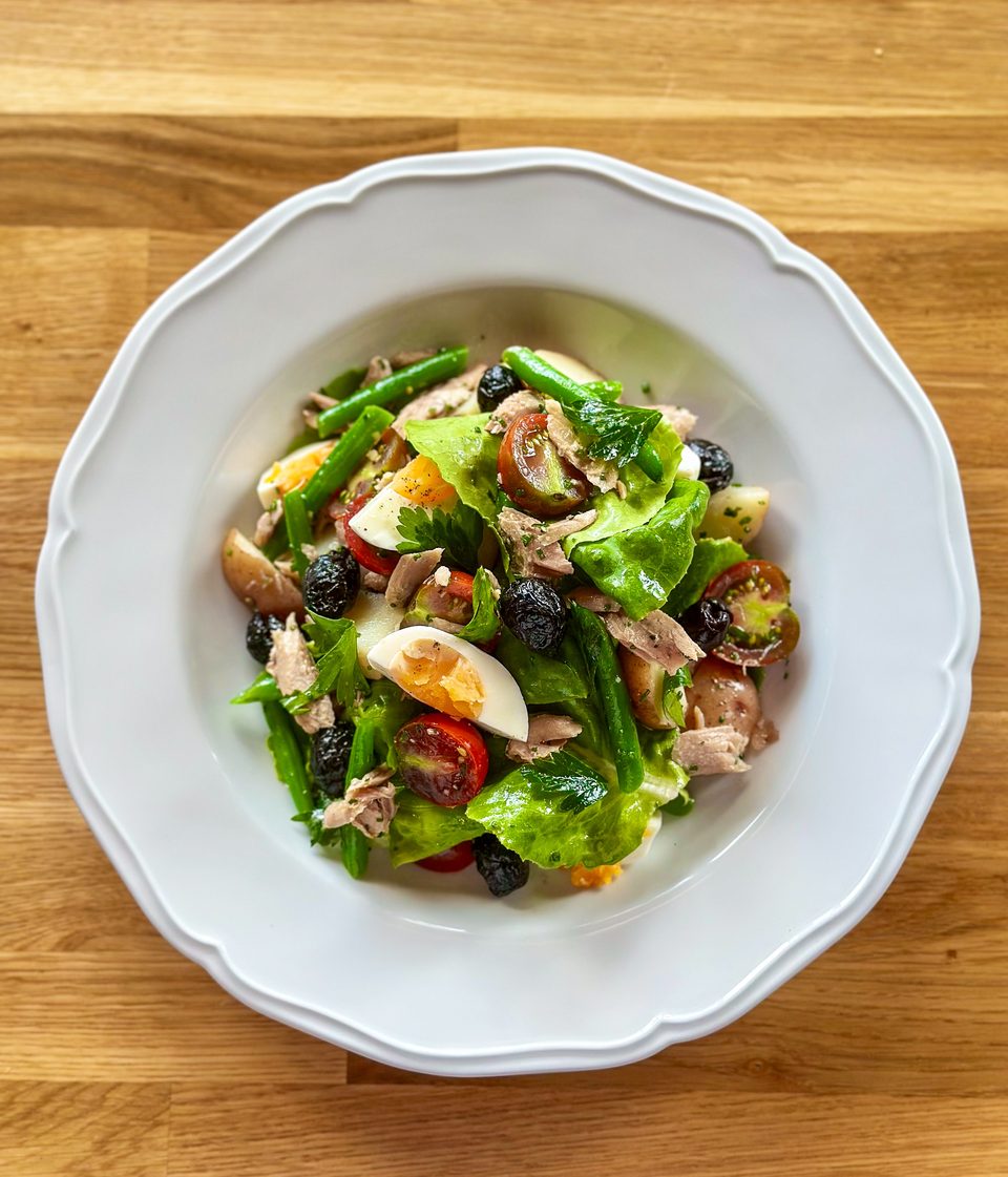 A vibrant Niçoise salad with tuna, green beans, olives, tomatoes, and hard-boiled eggs.